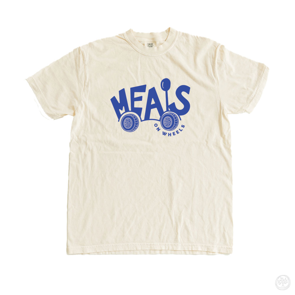 Natural cream-colored t-shirt with playful blue lettering and wheel graphics reading “Meals on Wheels” – nonprofit tee supporting senior meal delivery and food accessibility programs.